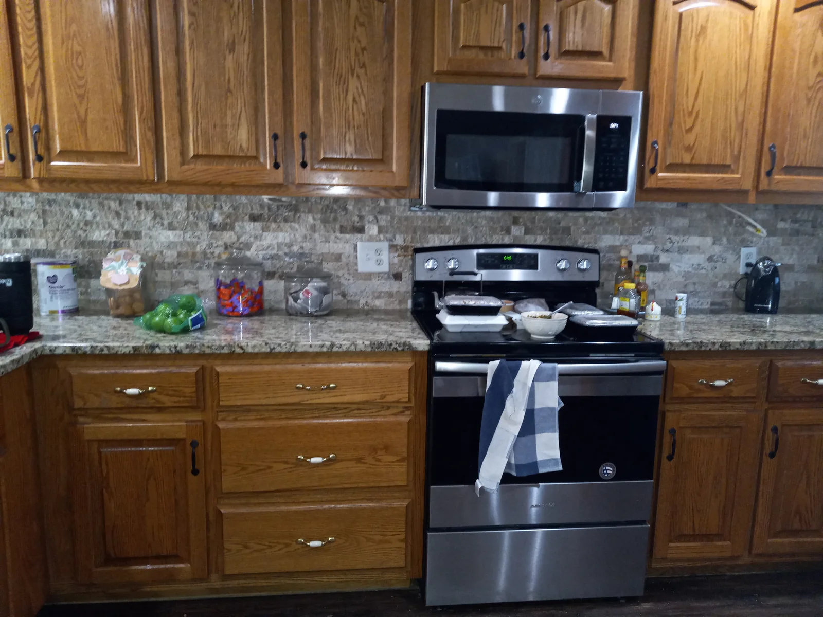 Kitchen with wood cabinets, tile backsplash, and stainless range and microwave