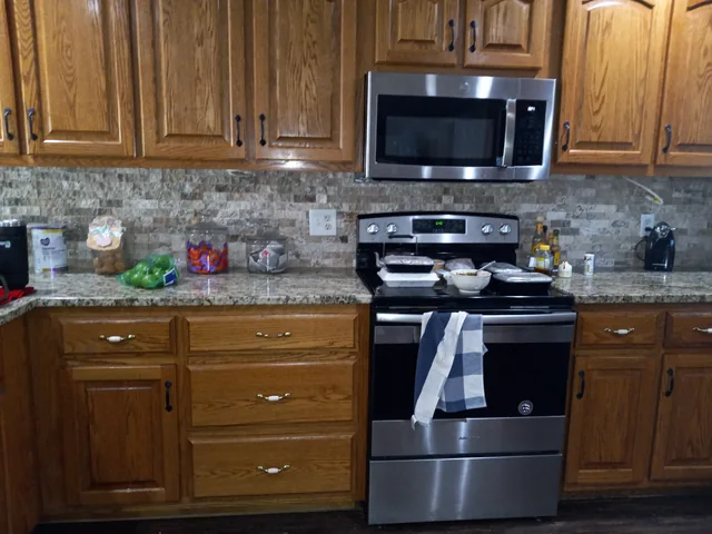 Kitchen with wood cabinets, tile backsplash, and stainless range and microwave