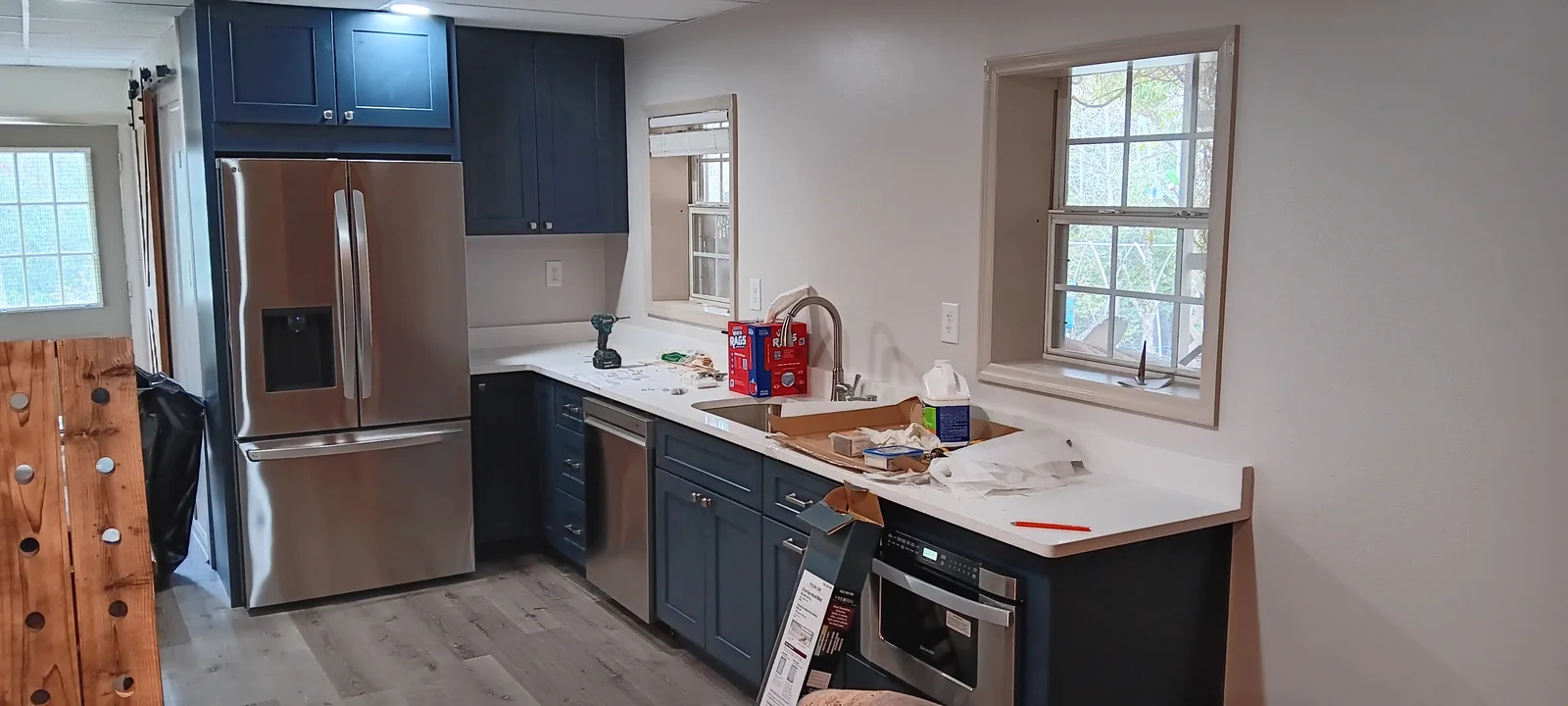 Deep blue kitchen cabinets with light counters and stainless appliances during installation