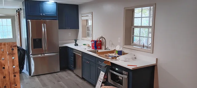 Deep blue kitchen cabinets with light counters and stainless appliances during installation