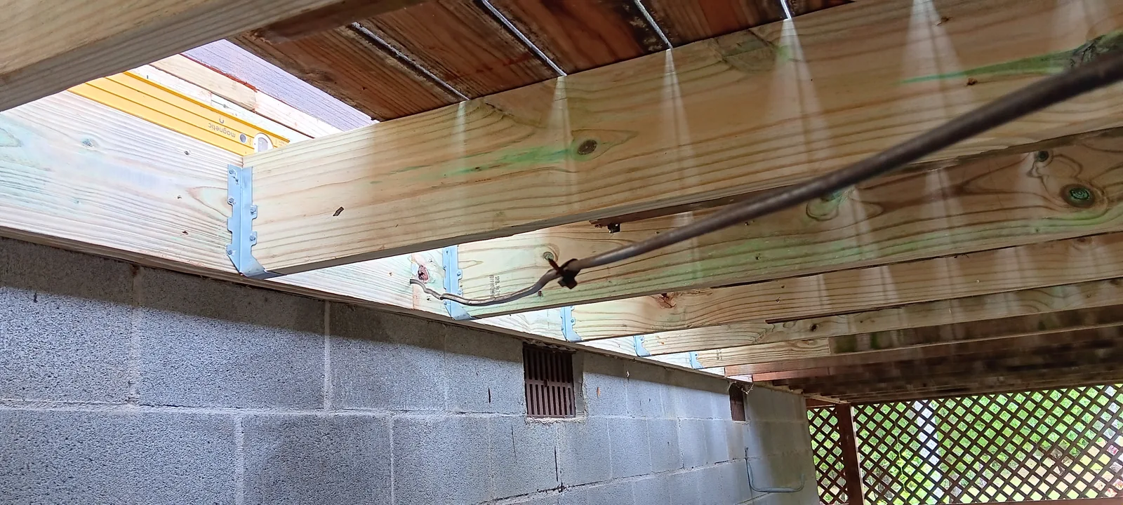 Timber deck framing and fasteners above a masonry foundation wall